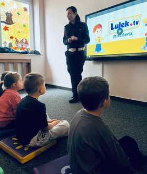 policjantka i dzieci na sali podczas prelekcji w tle ekran