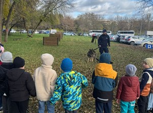przewodnik psa słuzbowego i jego pies widac grupę dzieci przed komendą