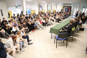 na sali grupa uczniów w tle policjantka stoi trzyma mikrofon