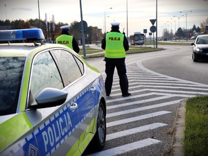 dwaj policjanci i radiowóz na ulicy  w tle autobus