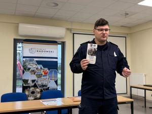 policjant trzyma w ręku ulotkę informacyjną