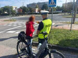 policjant stoi tyłem kontroluje trzeźwość rowerzystki