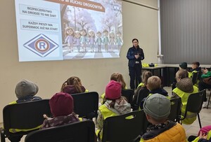 policjantka i grupa przedszkolaków w sali podczas prelekcji w tle ekran
