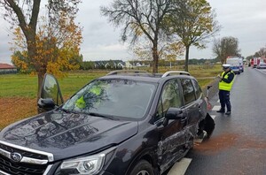 miejsce wypadku, na drodze uszkodzony pojazd, policjant wykonujący czynności przy aucie