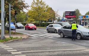 miejsce wypadku, policjant przy aucie, które potrąciło rowerzystkę,  w tle radiowóz i przejezdzające obok auta
