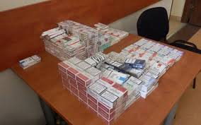 zdjęcie przedstawia kilkadziesiąt paczek papierosów różnych marek ułożonych w stos na stole
