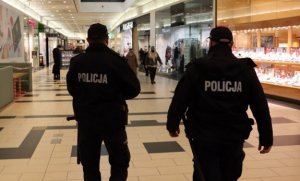dwóch umundurowanych policjantów znajdujących się na pasażu galerii handlowej