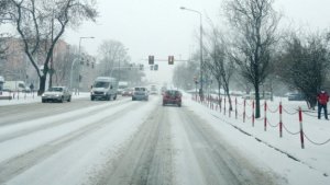 grafika przedstawia zaśnieżoną drogę po której poruszają się pojazdy