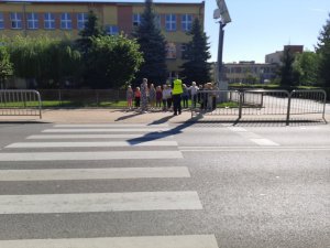 Dzieci z policjantem przy przejściem dla pieszych.