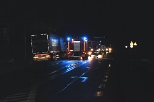 droga nocą, w oddali samochód ciężarowy i służby ratunkowe