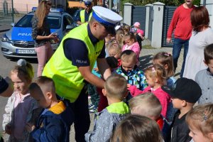 policjant rozdaje dzieciom elemnty odblaskowe