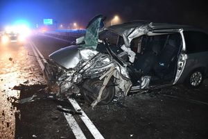Fotografia kolorowa: wypadek drogowy droga relacji Mława - Szydłowo, widzimy na drodze zniszczony pojazd marki Dodge.