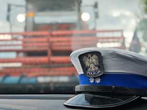 Fotografia kolorowa: czapka policjanta i w tle kombajn.