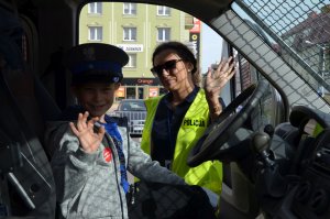 Fotografia kolorowa. Na zdjęciu widać chłopca w samochodzie policyjnym wraz z profilaktykiem z KPP w Mławie.
