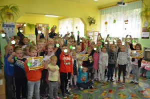 Fotografia kolorowa przedstawiająca profilaktyków z KPP w Mławie wraz z dziećmi promujących akcję Kierowco! Nie polujemy na zebrach.