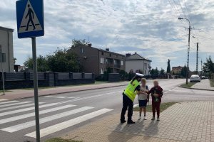 chodnik, policjantka podaje odblaski dwójce dzieci