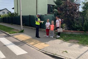 policjantka wręcza odblaski trójce dzieci i kobiecie