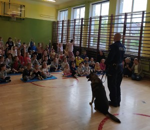 Policjant przewodnik z psem na sali gimnastycznej w towarzystwie dzieci