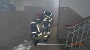 Strażacy podczas akcji gaśniczej w zadymionym korytarzu ostrowskiej komendy