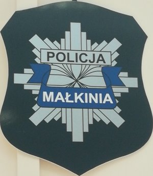 Gwiazda z napisem Policja, na niebieskiej wstążce napis Małkinia