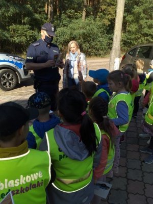 Policjant z dziećmi rozmawia o bezpieczeństwie w ruchu drogowym