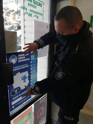Dzielnicowy umieszcza plakat w urzędzie gminy
