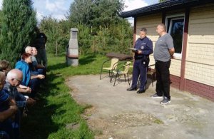 umundurowany policjant przeprowadzający spotkanie z działkowcami na terenie ogródków działkowych w Sierakowie