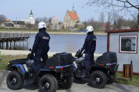 Dwóch policjantów stoi na quadach nad jeziorem