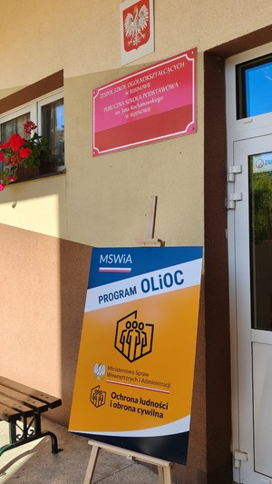 Zdjęcie budynku szkoły i tablicy OLiOC.