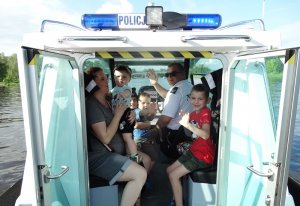 Policjant omawiający specyfikę pracy na wodzie. Dzieci zwiedzające policyjną łódź.