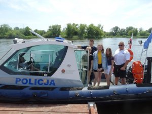 Policjant omawiający specyfikę pracy na wodzie. Dzieci zwiedzające policyjną łódź.