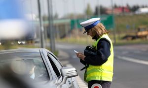 Zdjęcie przedstawia policjantkę stojącą przy samochodzie