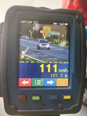 Zdjęcie przedstawia wyświetlacz urządzenia do pomiaru prędkości. Widać na nim zdjęcie srebrnego pojazdu jadącego w kierunku policjantów. Urządzenie wskazuje prędkość 111 km/h i odległość 187,3 m od pojazdu do mierzącego prędkość policjanta