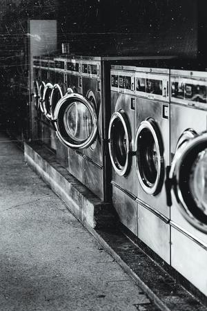 Czarno-białe zdjęcie przedstawia stojące w rzędzie pralki