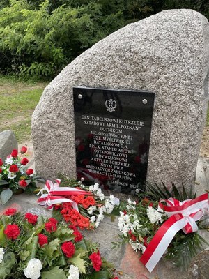 Kamień z czarną tablicą upamiętniającą poległych żołnierzy w Załuskowie