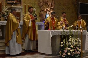 Księża i biskup stojący w środku modlą się przy ołtarzu