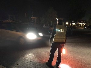 Umundurowany policjant w kamizelce odblaskowej z włączoną latarką obserwuje wieczorem jadący samochód