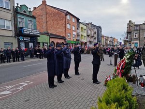 Policjant i strażacy salutują przed pomnikiem Piłsudskiego