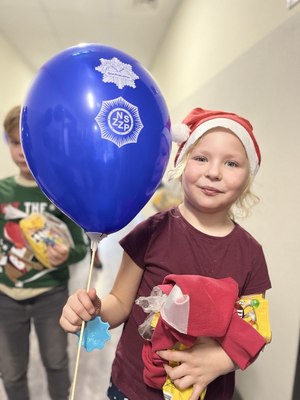 Dziewczynka w czapce Mikołaja z niebieskim balonem