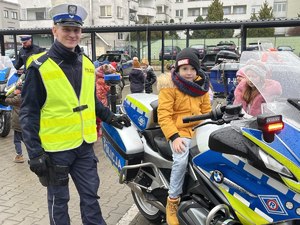 Policjant stoi przy motocyklu na którym siedzi dziecko