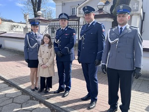 Trzech policjantów, policjantka i dziewczynka stoją na chodniku