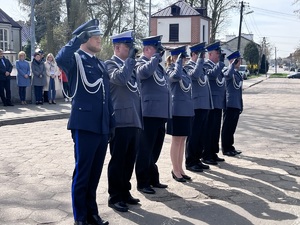 Policjanci i policjantka oddają honor przed pomnikiem