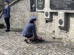 Policjantka klęka przy pomniku i kładzie kwiaty
