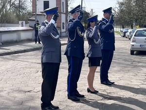 Trzech policjantów i policjantka salutują przed pomnikiem