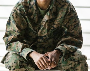 Zdjęcie przedstawia sylwetkę kobiety od szyi w dół. Kobieta ubrana jest w mundur wojskowy
