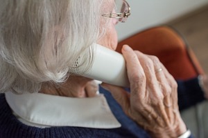 Starsza kobieta trzymająca słuchawkę przy uchu