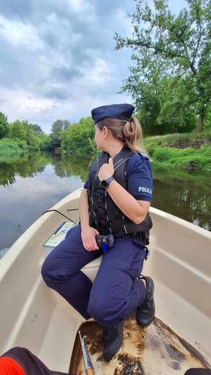 Policjantka w kamizelce ratunkowej płynie łodzią po rzece