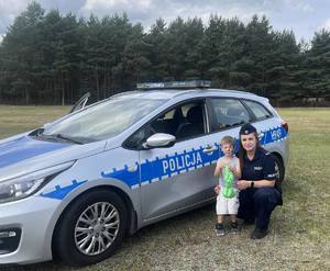 Policjantka z dzieckiem przy radiowozie