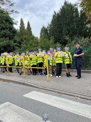 Dzieci z policjantką stoją na chodniku