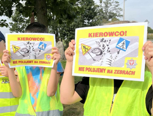 Dzieci z plakatem z napisem Kierowco nie polujemy na zebrach